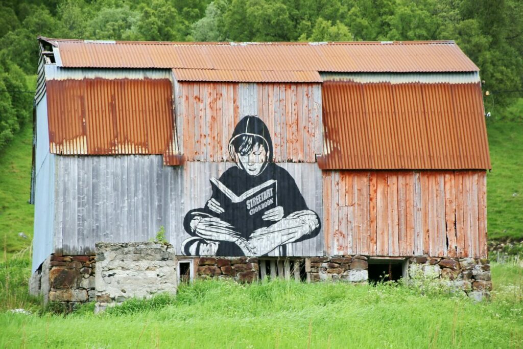 old shed with large mural of boy reading a book on it