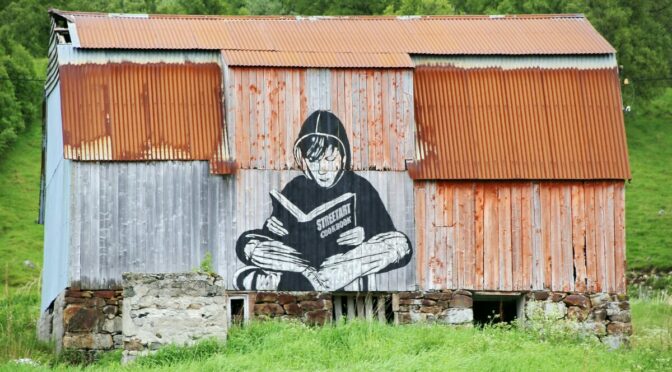 old shed with large mural of boy reading a book on it