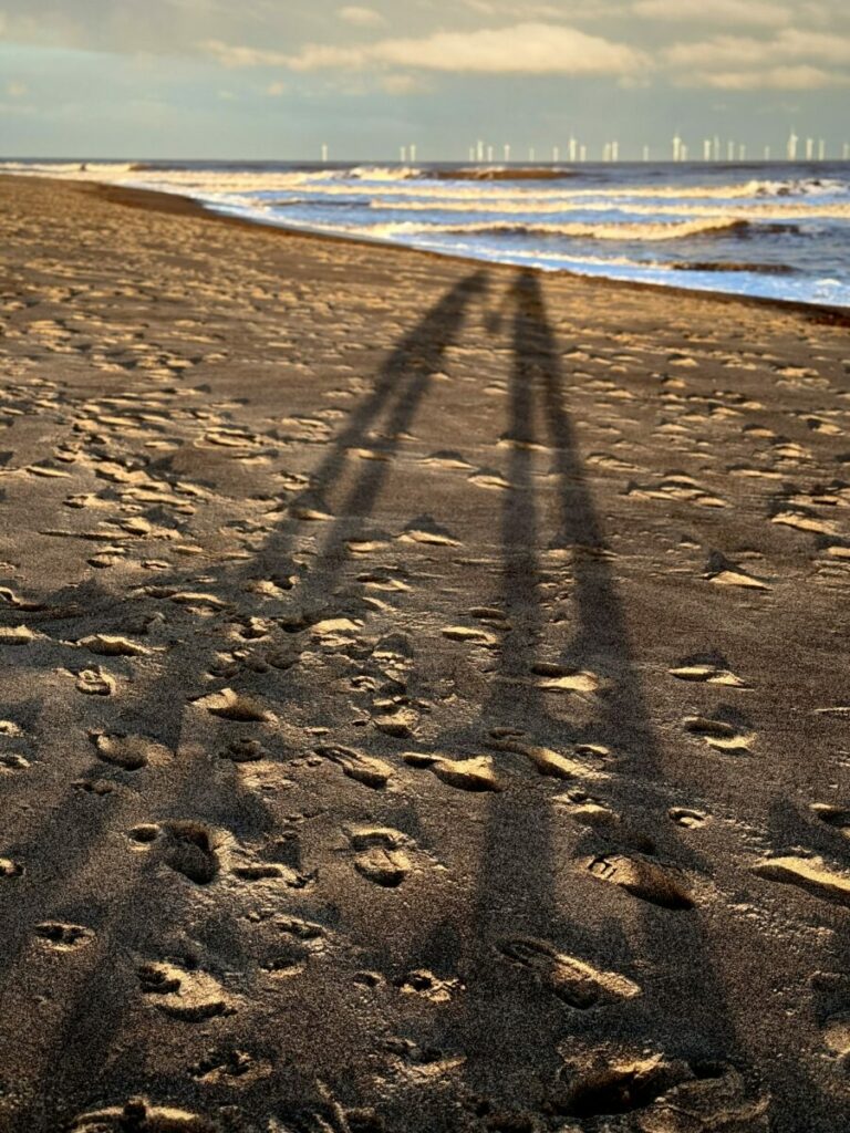two long human shadows on beach