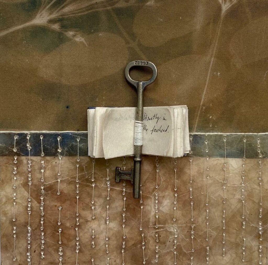 large key placed in middle of open, tiny book, with mobile strands hanging from below it