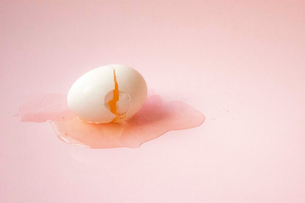 Photo of broken egg on pink background