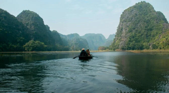 Flat boat with rowing people in dark gray waters
