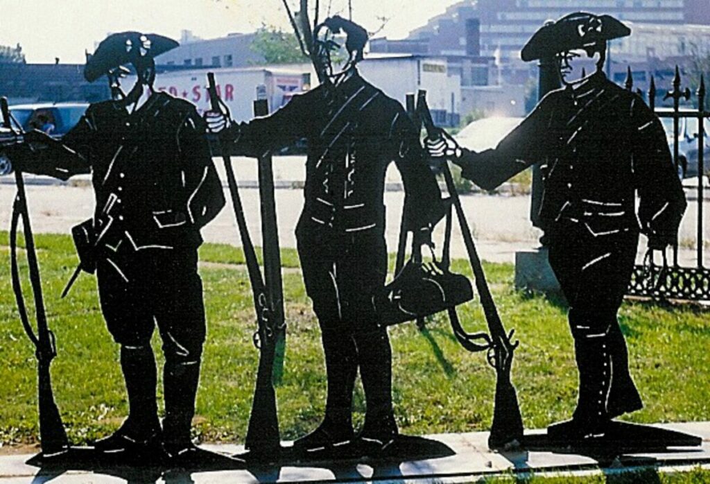 Sculptures of three minute men, standing with their guns