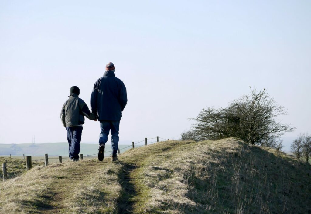 Photo of adult and child walking up a ridge