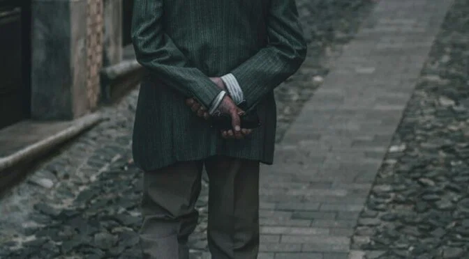 Photo of man from behind, with arms crossed behind his back
