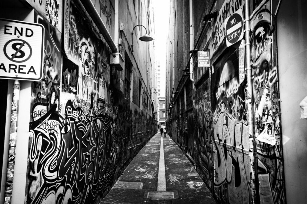 Black and white photo of alleyway with graffiti painted on both side walls