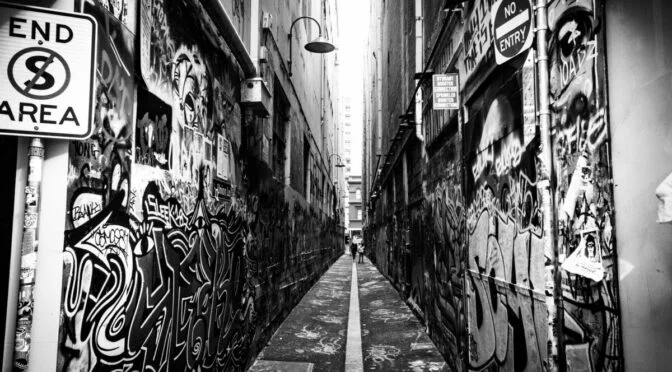 Black and white photo of alleyway with graffiti painted on both side walls