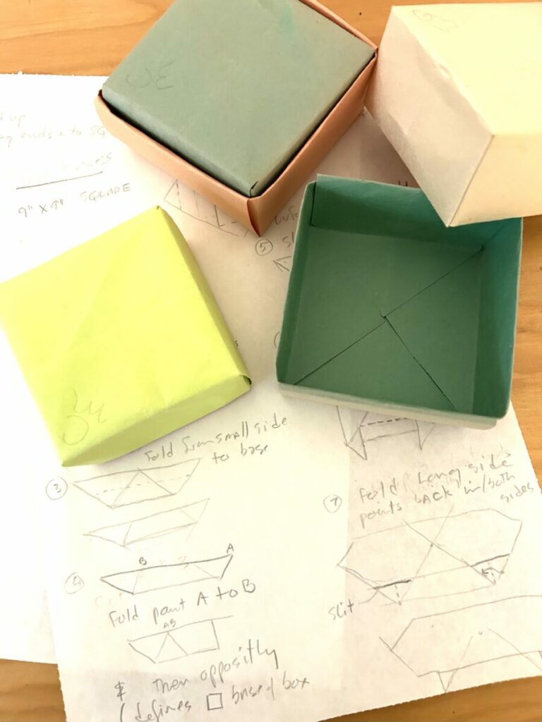 Photo of paper made boxes on paper with diagrams on it