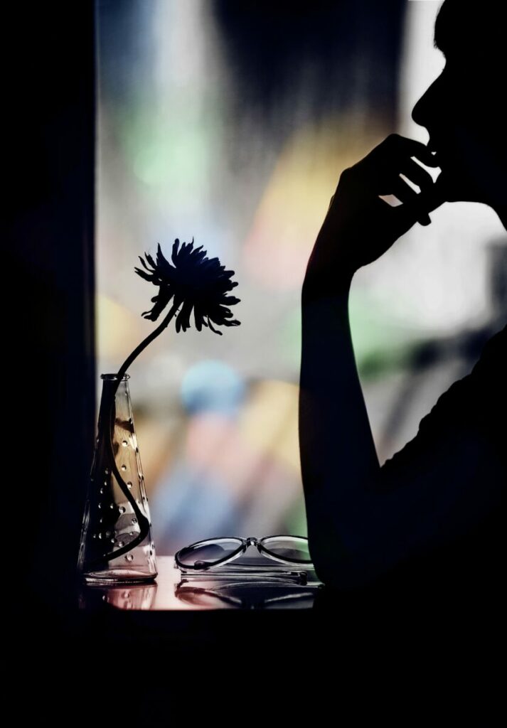 Photo of silhouette of woman with vase on table against blurred window